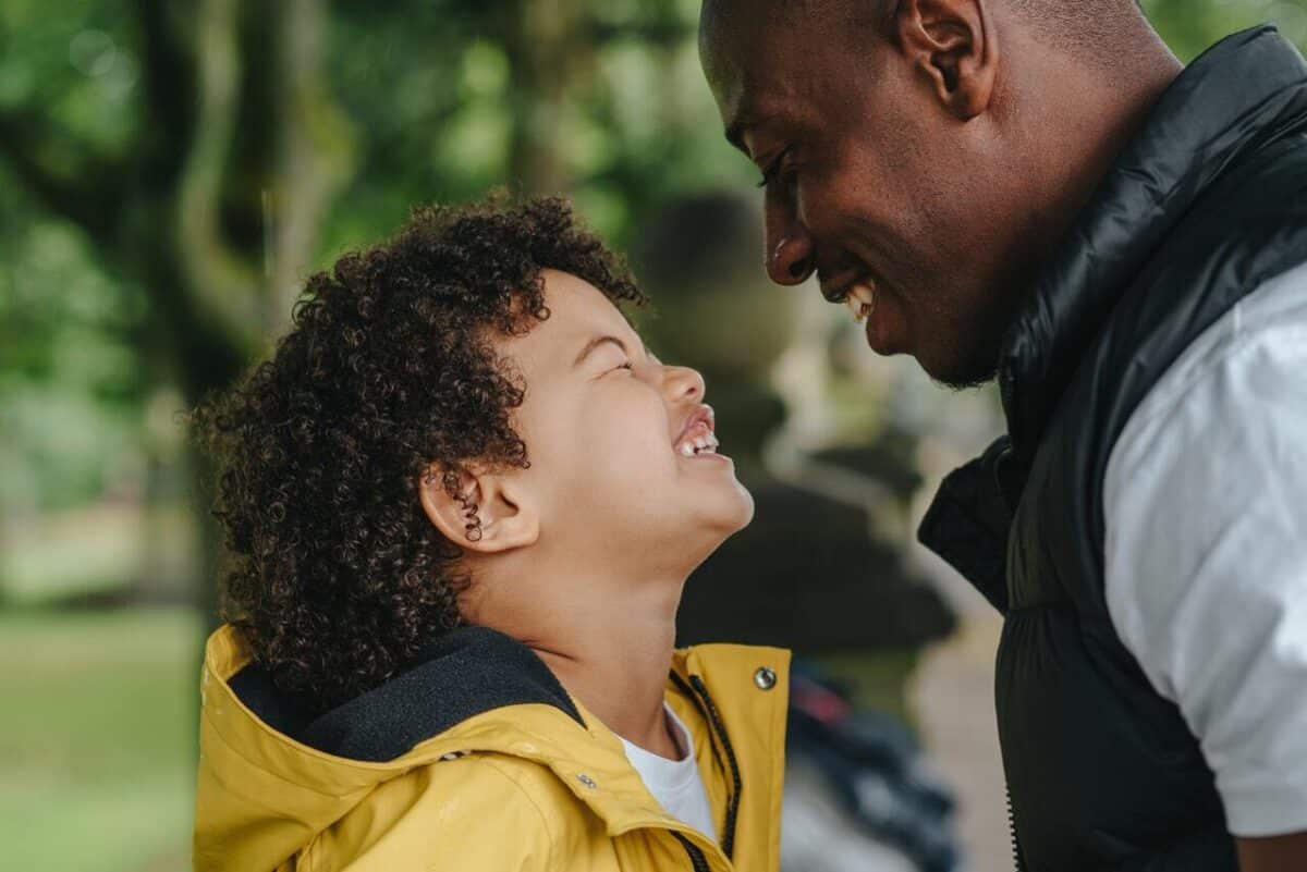 Man and young son in park laughing and smiling after receiving divorce advice for men